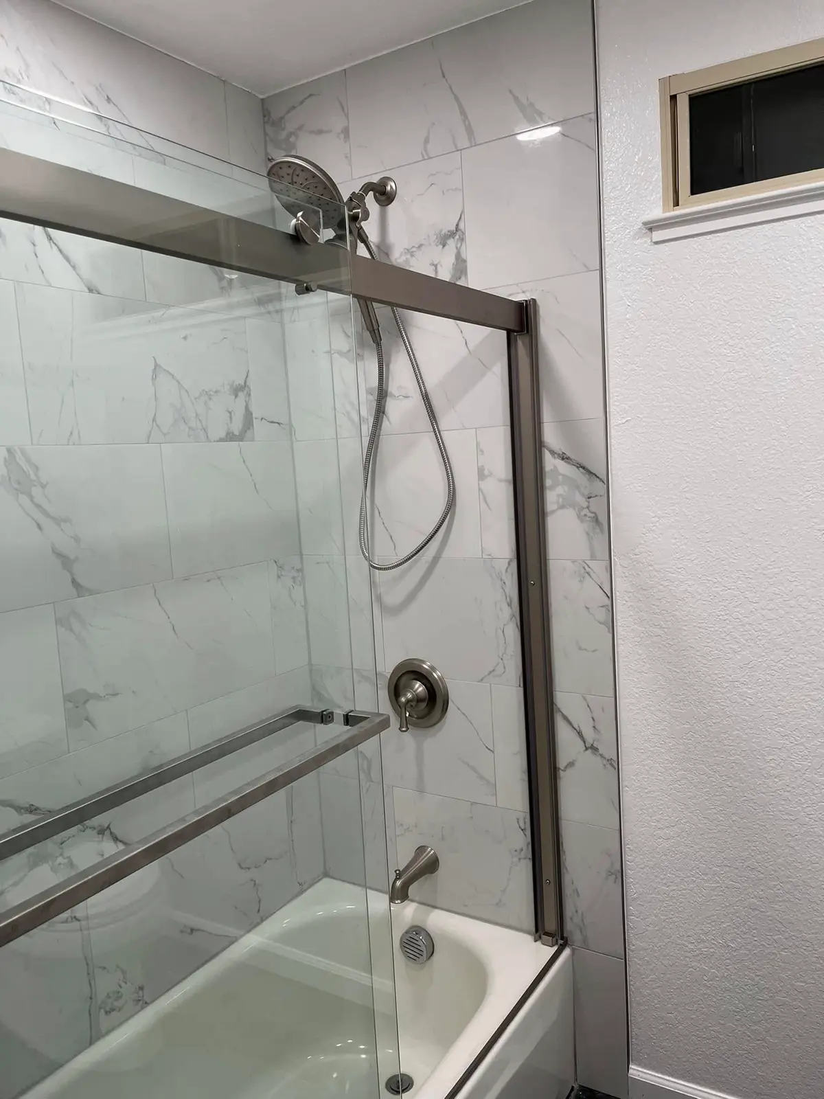 Bathroom remodeler in Vallejo finishing a marble-look tile shower with glass door