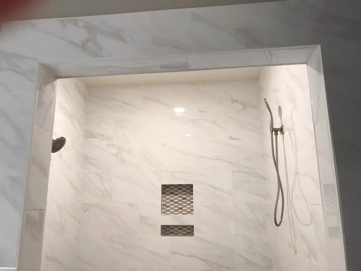 Tile contractor in Vallejo: marble-look shower wall with mosaic niche