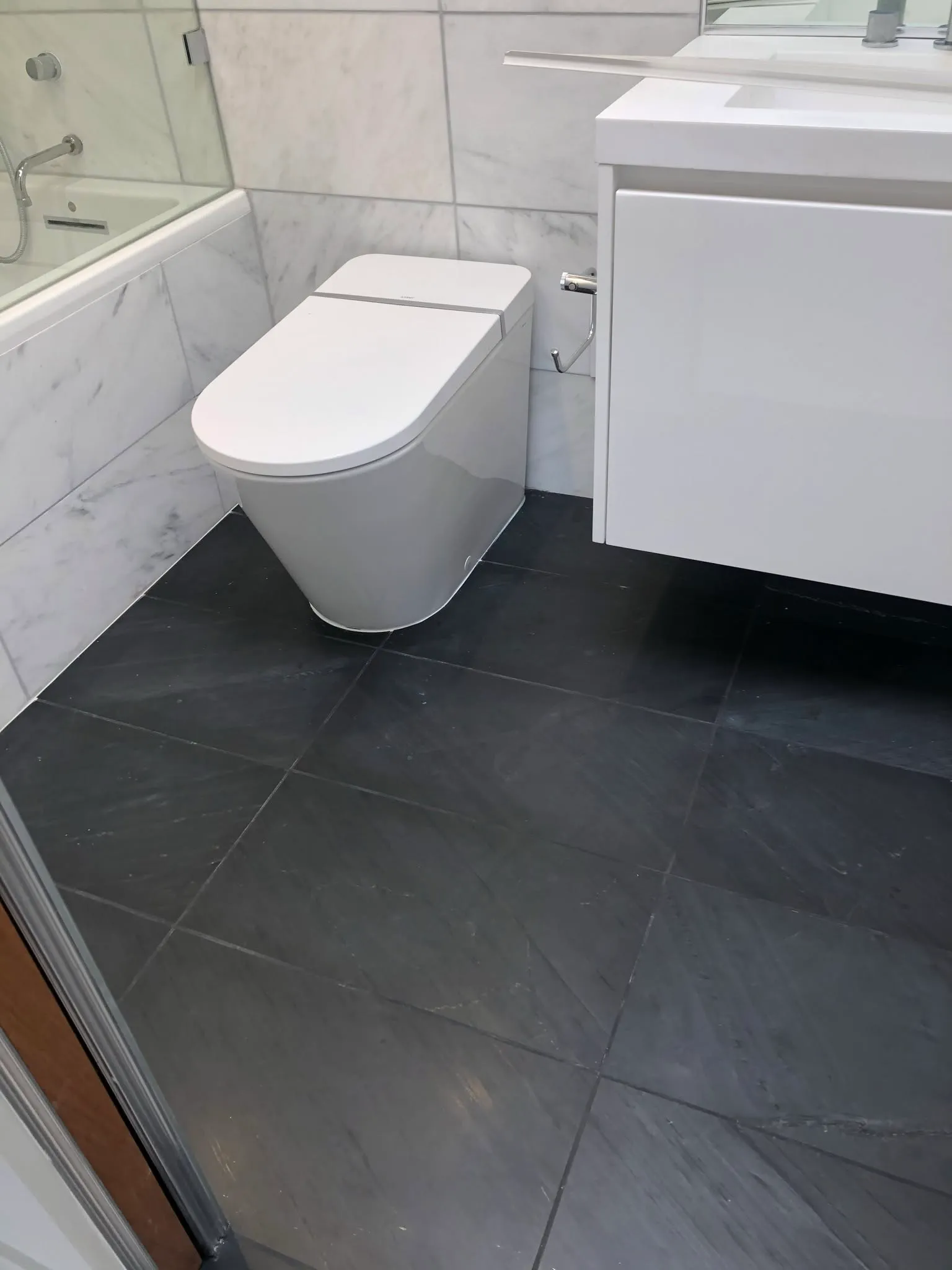 Modern wall-mounted vanity and toilet on dark tile in a Vallejo bathroom