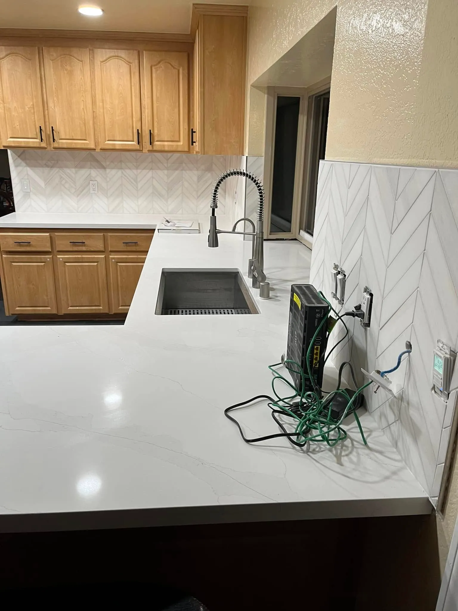 Quartz countertop and chevron tile backsplash beside a new kitchen sink in Vallejo